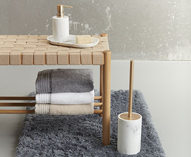 BERGHEIM badrumstillbehör i ett badrum med en bänk och handdukar 