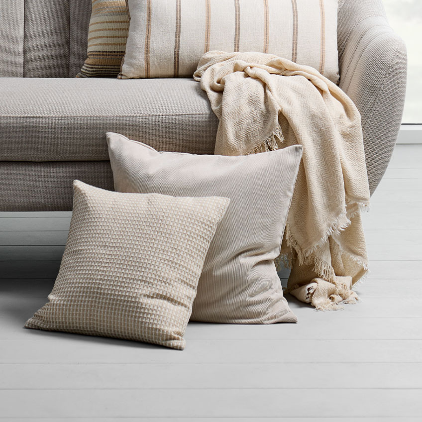 Decorative cushions in different shades of sand, beige, and warm whites 