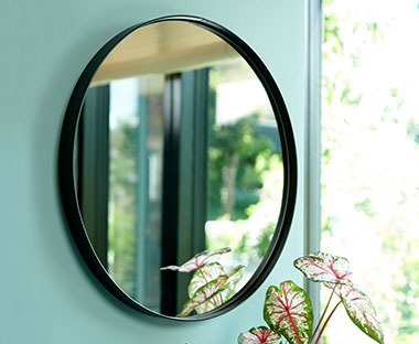 MARSTAL rund spegel på en vägg bredvid en blomma 