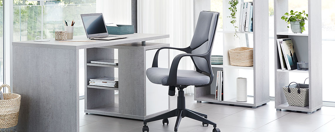 Grått skrivbord och en grå svart kontorsstol i ett hemmakontor 