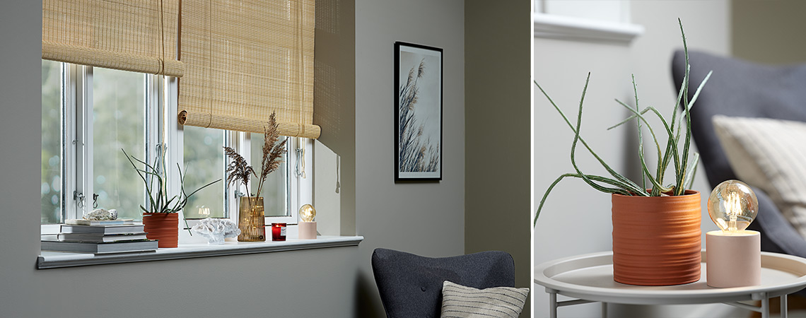 Dekoration vid fönsterbrädan bestående av en kruka växt, en prydnad, en vas, en doftljus och en batterilampa