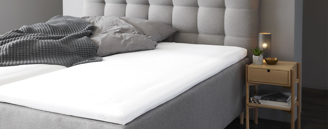 Sovrum med grå king size-säng med madrass och grå kudde och täcke