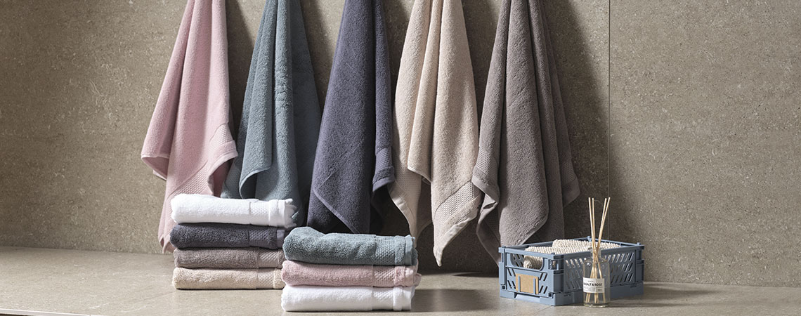 Handdukar i olika färger hängande i ett badrum