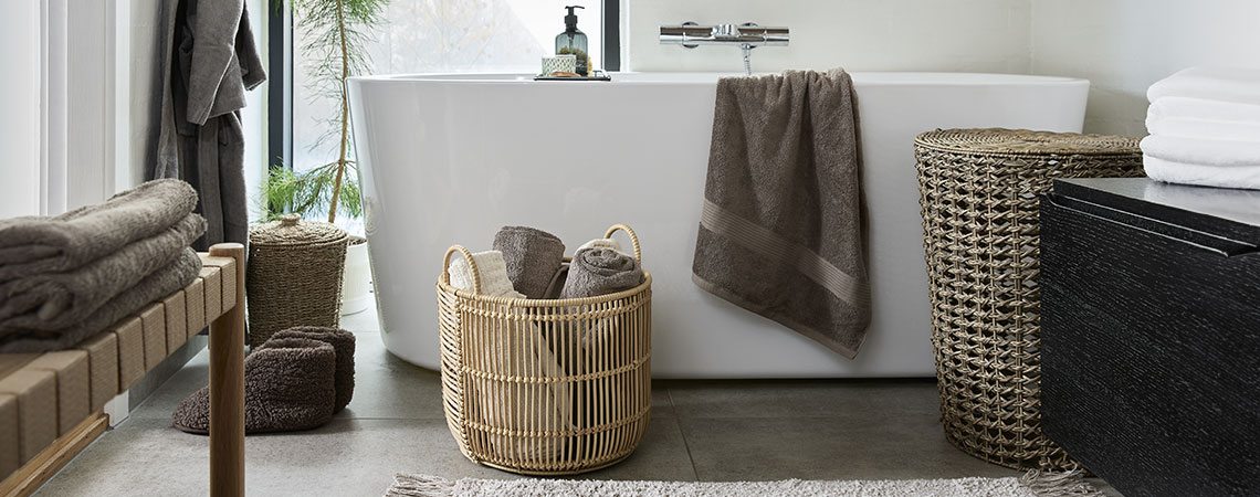 Korg med handdukar, tvålpump och tvättkorg i badrum