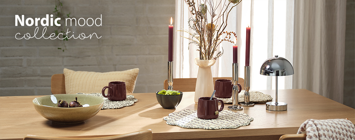 Matbord med skålar, muggar, bordsunderlägg och vas, ljusstakar och batterilampa