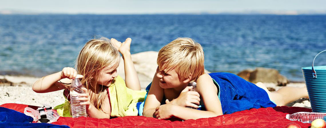 Två barn som hänger på stranden och har en härlig sommardag