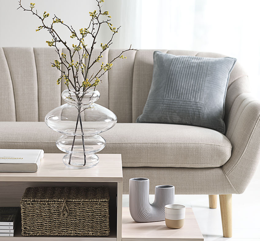 Ljust vardagsrum med lekfulla vaser på soffbord och beige soffa