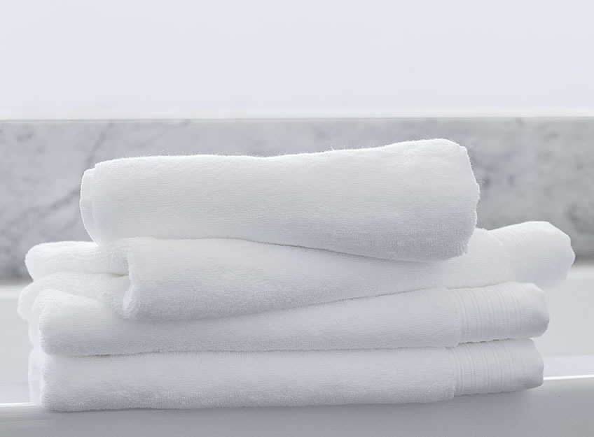Vita handdukar i en hög i ett badrum