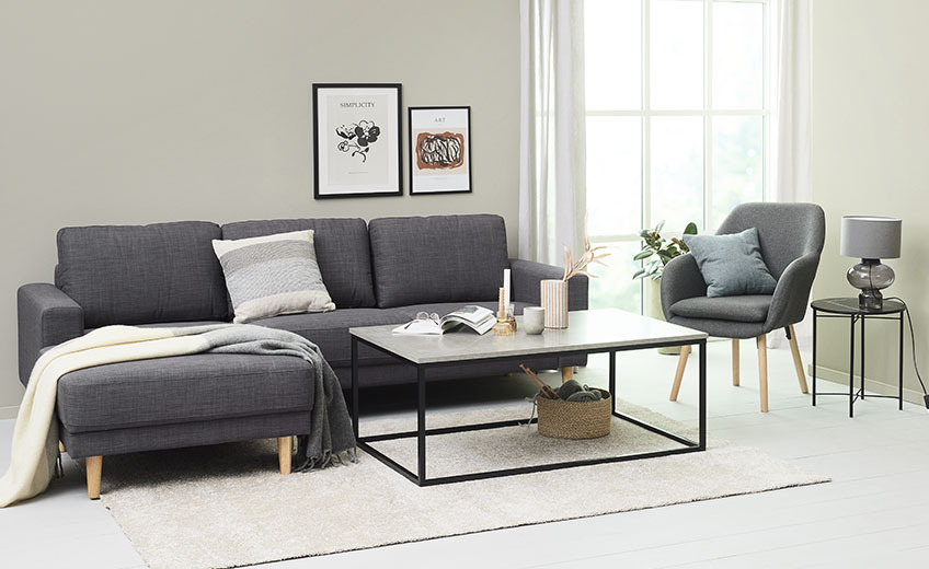 Vardagsrum med en ljusgrå matta, en fåtölj och en soffa med en kudde och pläd