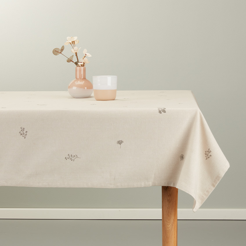 Duk på matbord i varm beige färg med vit och mjuk rosa mugg och vas