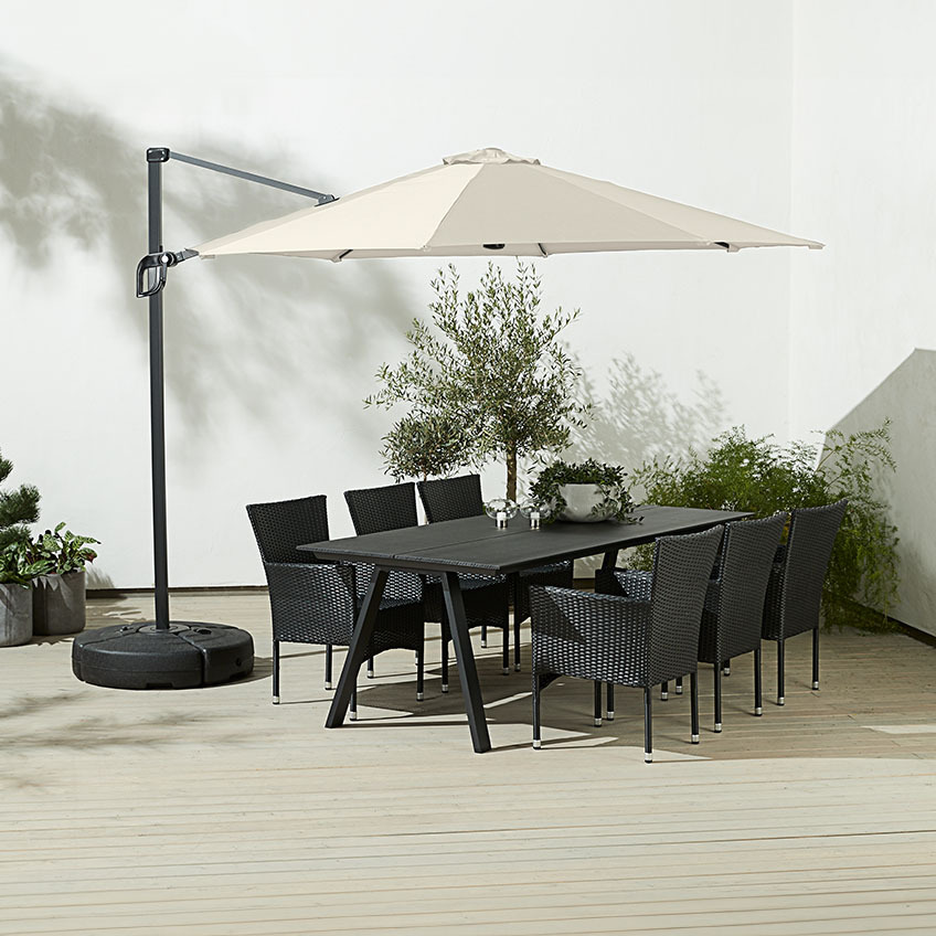 Stort, fyrkantigt off-white hängande parasoll ovanför matbord utomhus med trädgårdsstolar