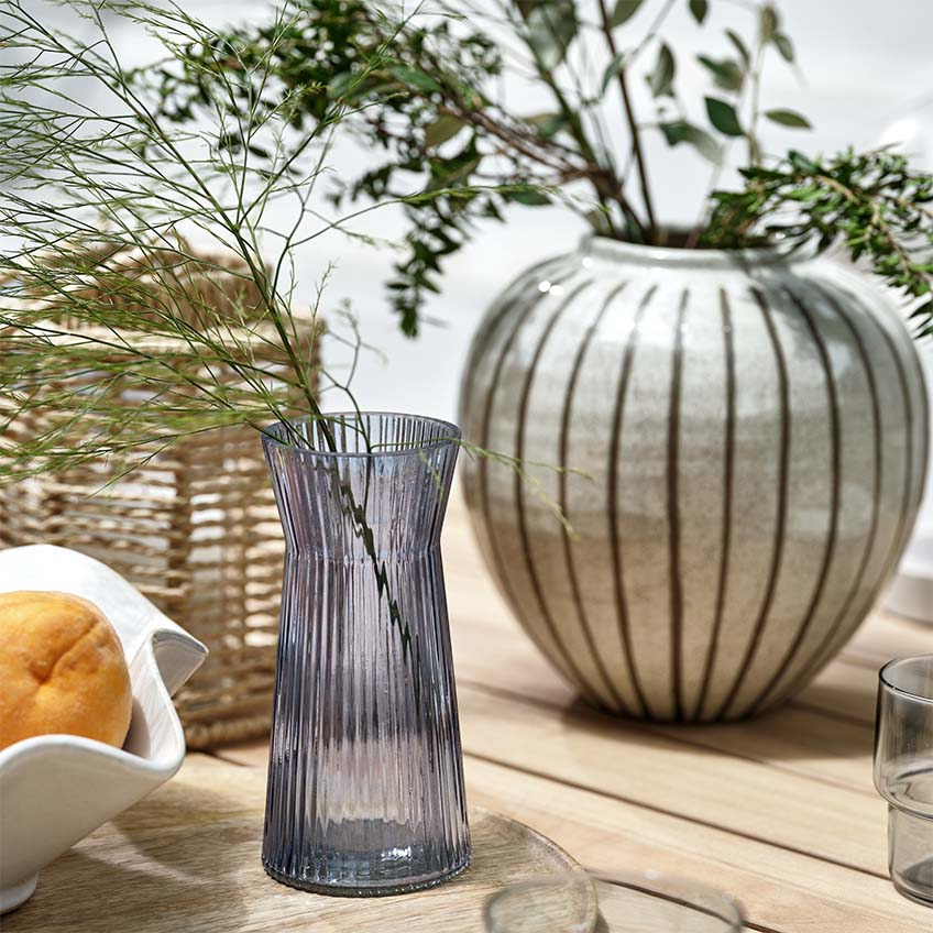 Vaser, lykta och skål på trädgårdsbord av trä utomhus