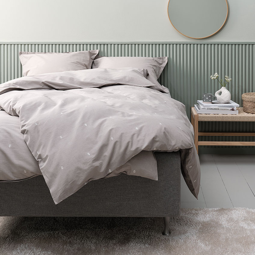 Ljusgrått påslakanset och sängkläder i bomull inklusive örngott på sängen i sovrummet