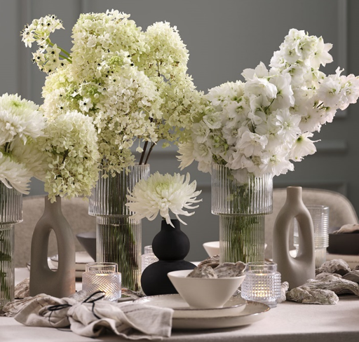 Svar och glasvas med blommor på ett bord med nyårsdukning