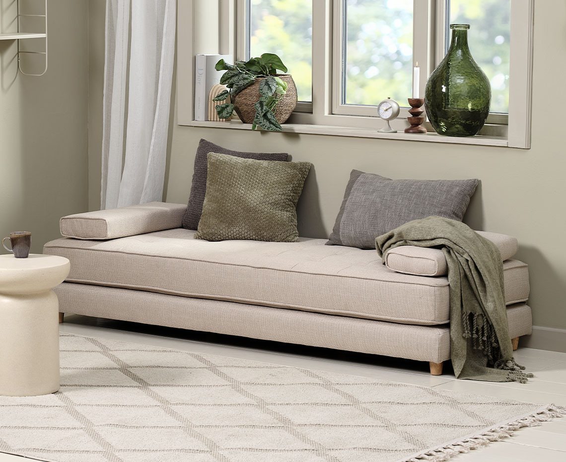 Beige daybed in living room with cushions and throw