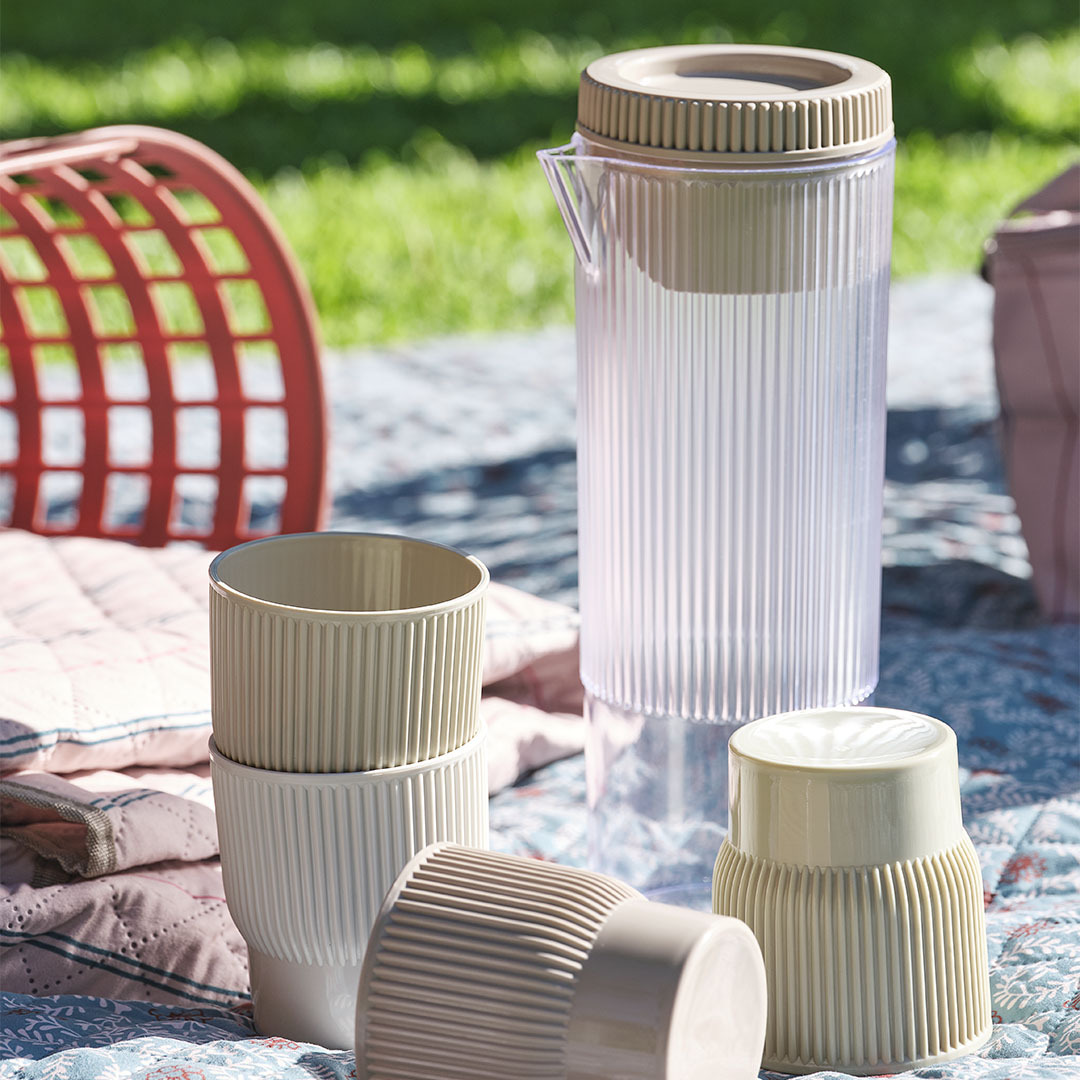 TJIM picknickkanna med fyra matchande koppar Picknickartiklar, inklusive en kanna med fyra matchande koppar på en picknickfilt