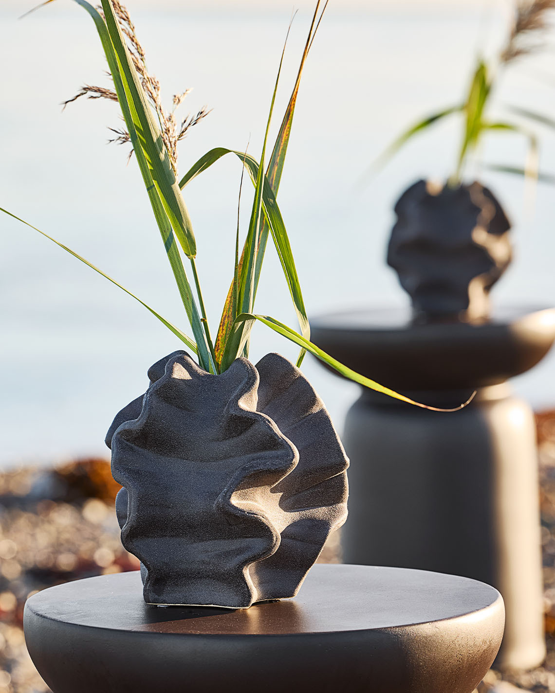 Hög vas på piedestal i sanddynerna nära en strand