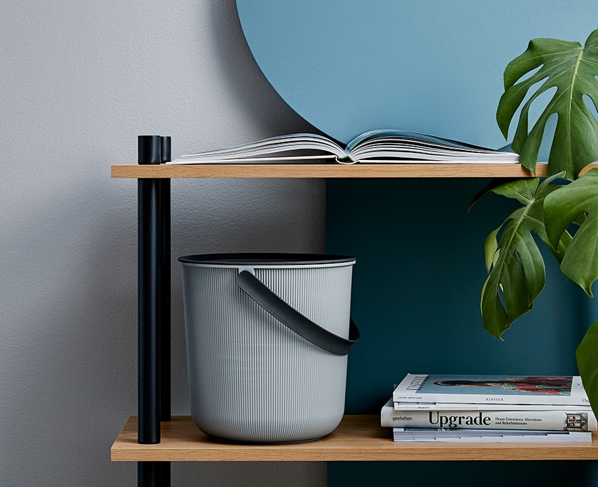 Storage bucket with a lid and a handle on a shelf a bookcase 