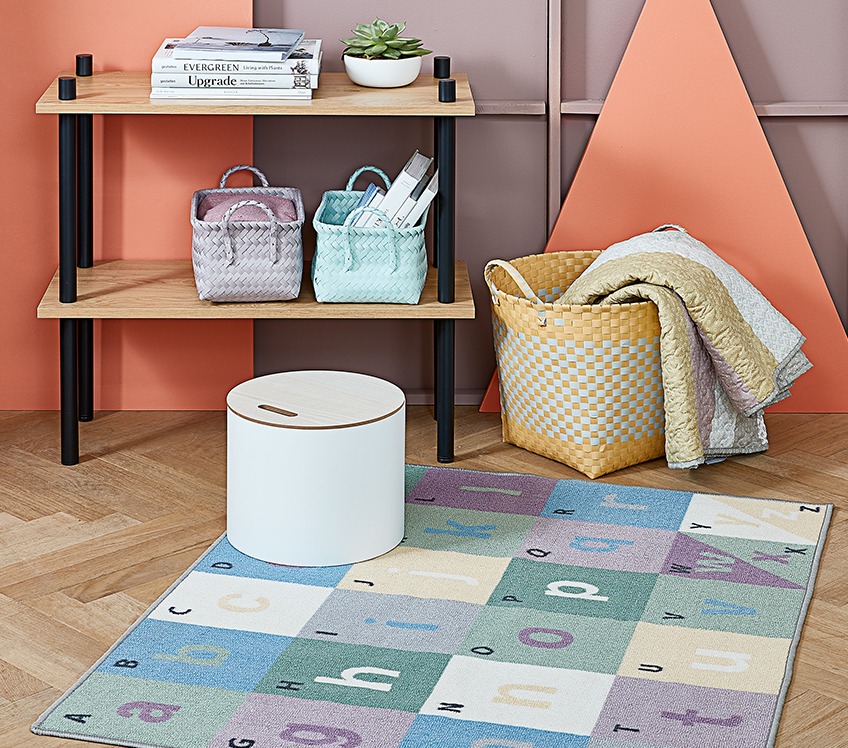 Room with kids rug on the floor, storage box and basket with throw