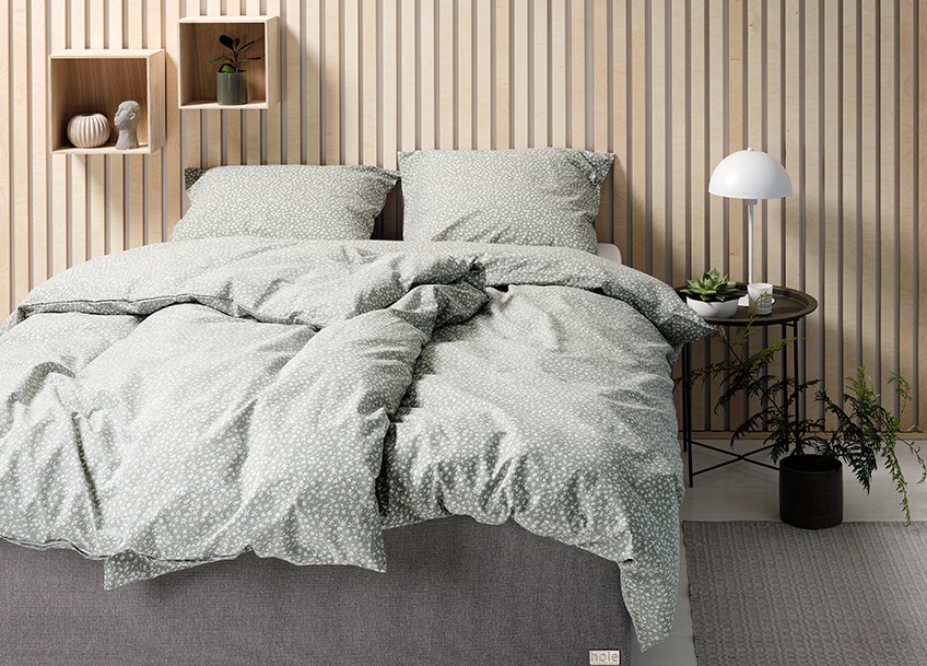 Ett sovrum med bäddad säng och nattduksbord