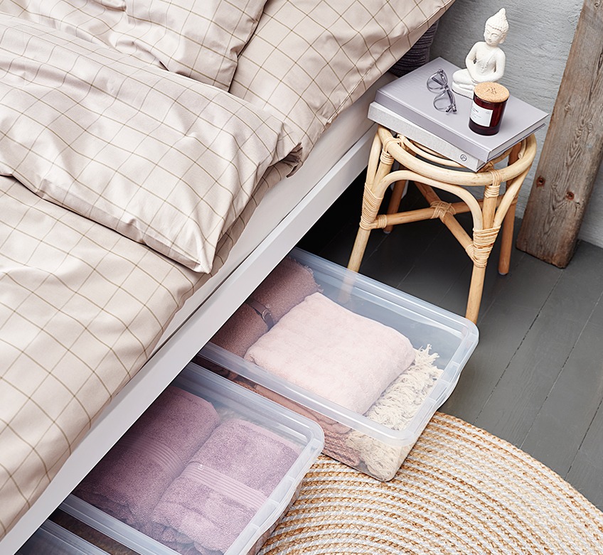 Säng bäddad med khakifärgat sängkläder och med förvaringslådor