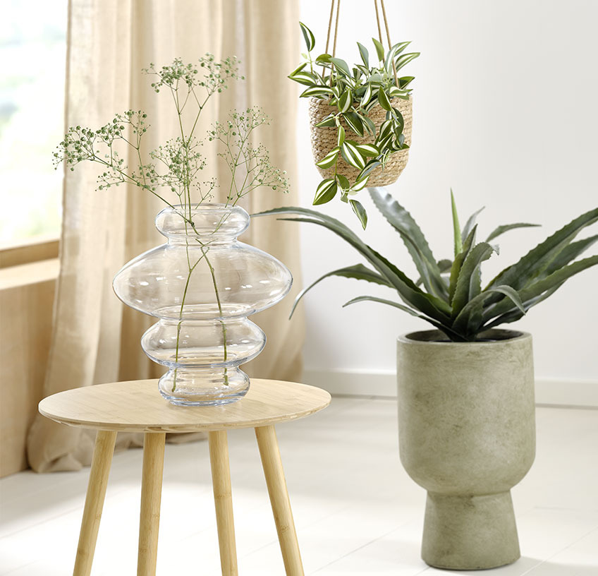 Glasvas på gavelbord, hängande växtkruka och grön växtkruka med konstgjorda växter