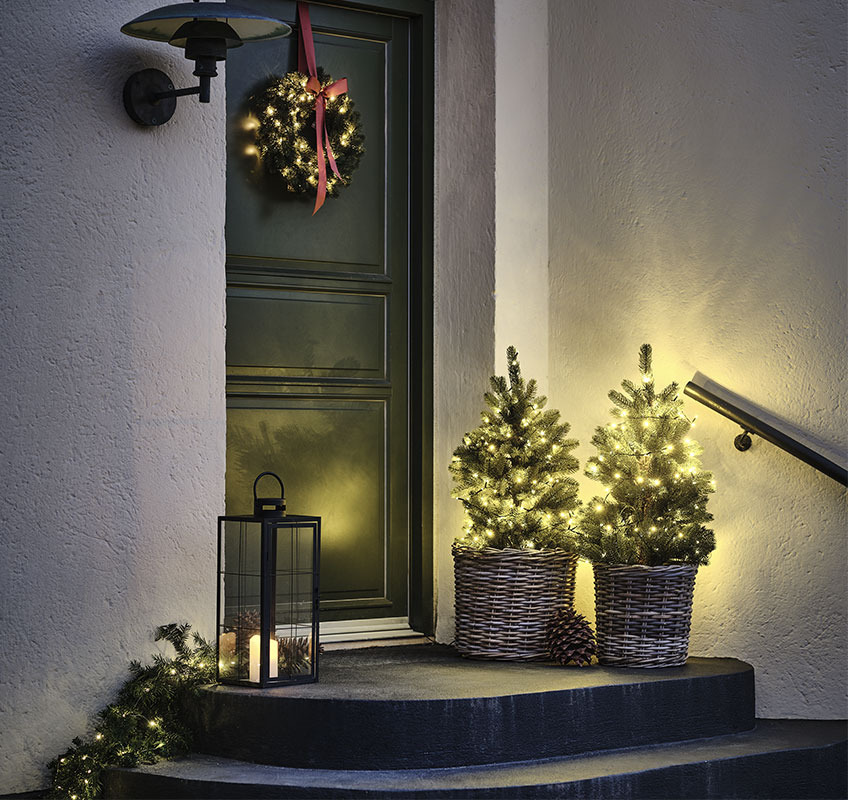 Två granar framför ytterdörren och julkrans med röd rosett