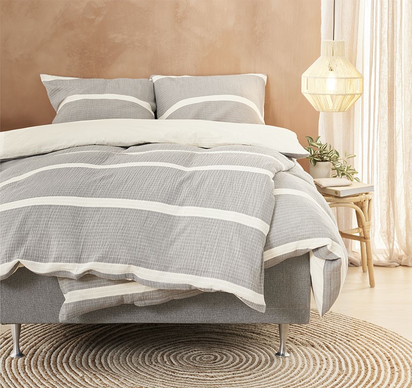 Säng med sängkläder i grå eller beige färger