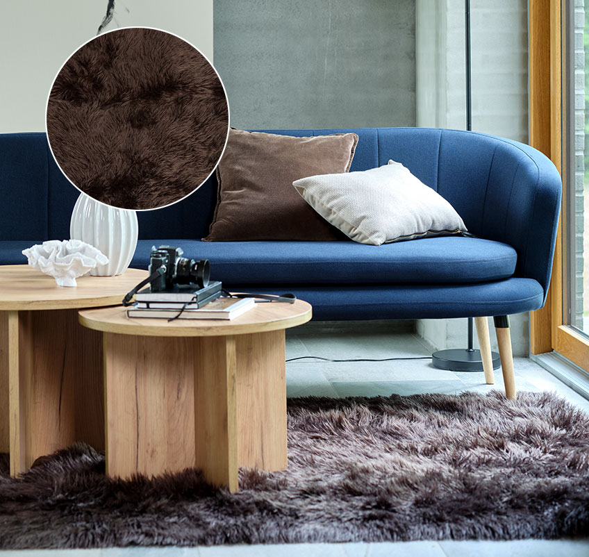 Vardagsrum med brun matta i fuskpäls, blå soffa och runda soffbord
