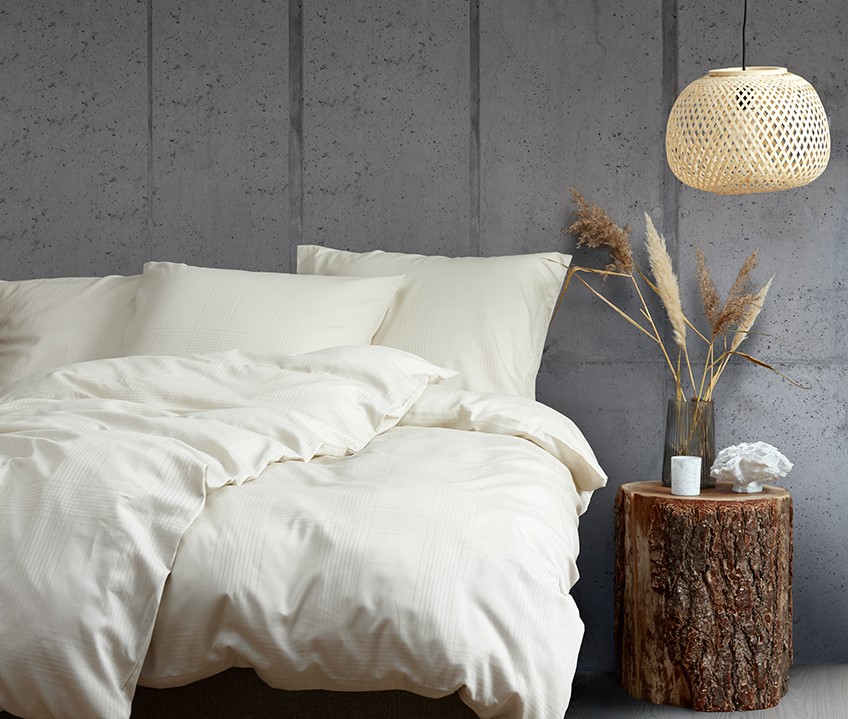 Elegant sovrum med lugnt nordiskt utseende och säng med sandfärgat sängkläder