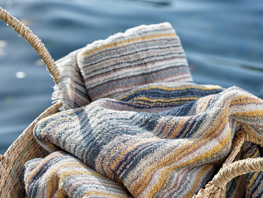 Flätad korg med randiga handdukar vid en sjö