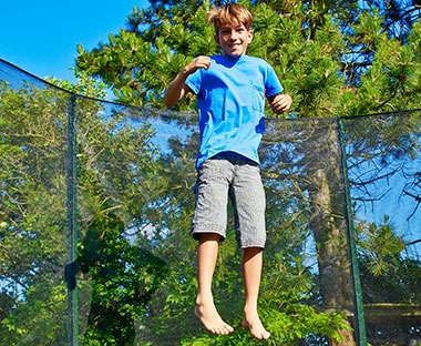 Pojke hoppar i en stor strudsmatta med säkerhetsnät 