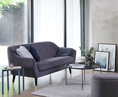 EGEDAL grå soffa i ett vardagsrum med soffbord och puff vid stora fönster  